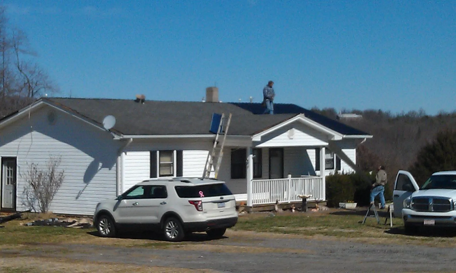 Roofers stripping shingles from a white ranch house roof in Somerset
